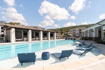 A pool with sun loungers and a building in the background.